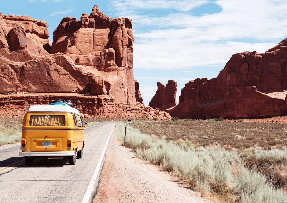 Yellow van on a desert road between red canyons